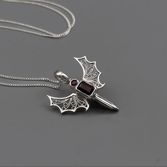 Silver archangel pendant with burgundy gemstones on a gray background